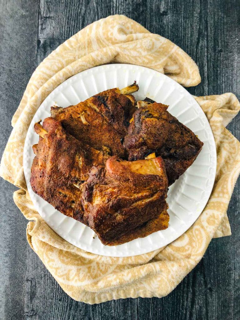 white dish with slow cooked middle eastern ribs on a beige towel