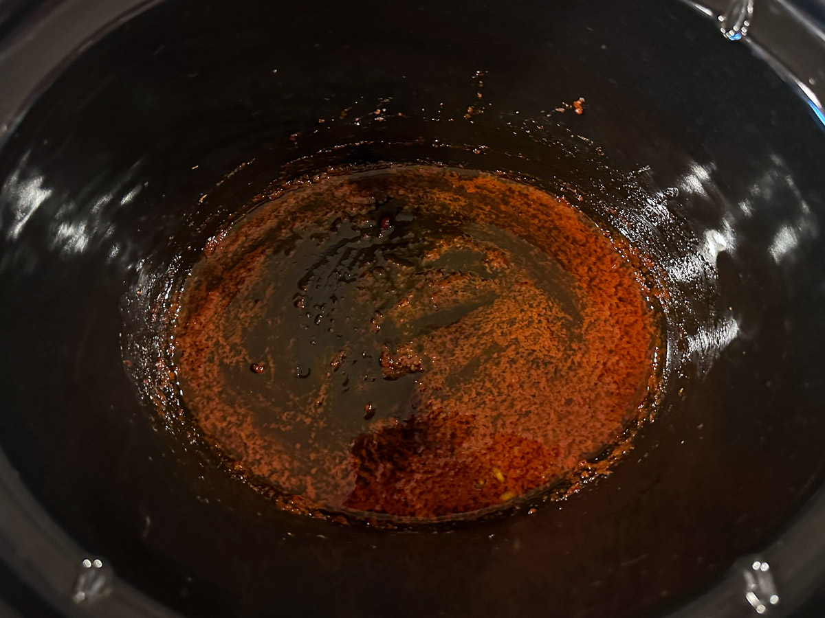 Black crockpot with the mixed oil, spices and sweetener.
