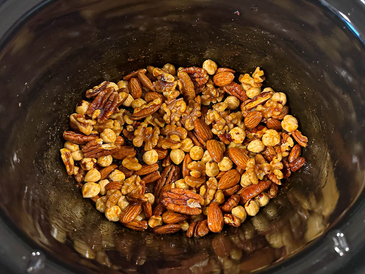 Slow cooker with the nuts mixed in the spices ready to cook.