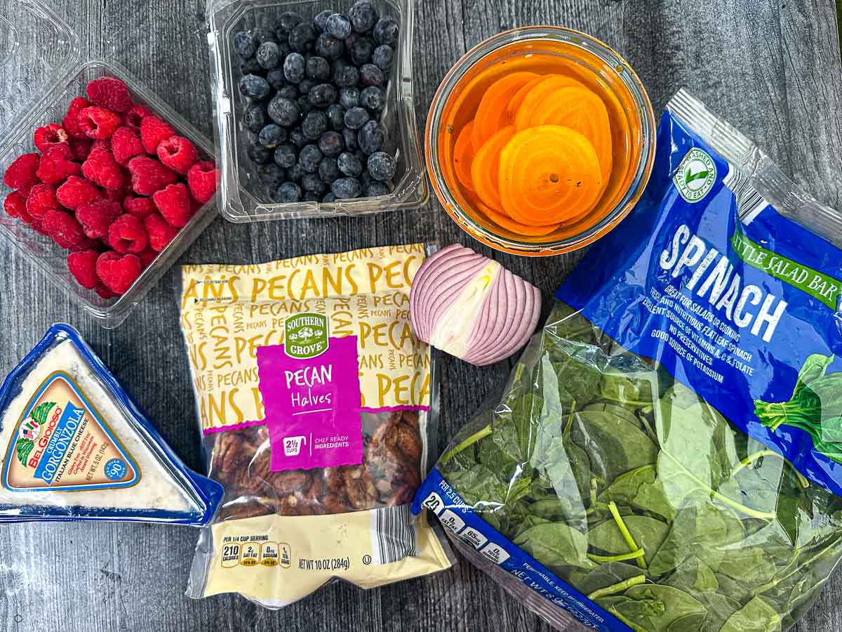 Salad ingredients - baby spinach, pickled golden beets, pecans, gorgonzola, blueberries, raspberries and red onion.