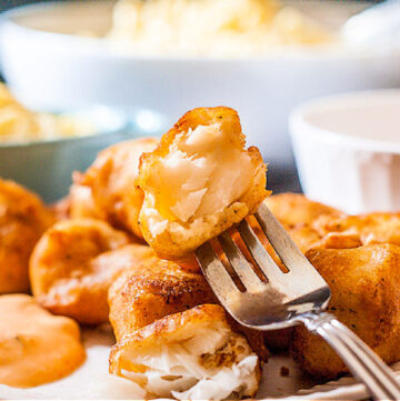 closeup of a plate of beer battered cod nuggets with a fish