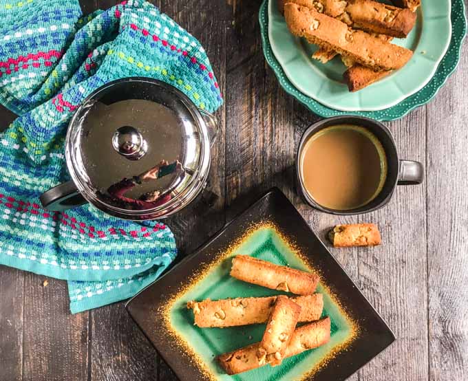 green and black plate with gluten free biscotti and coffee press with a cup of coffee