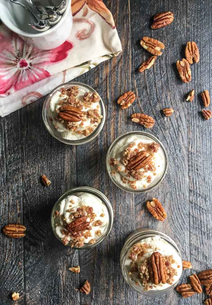 aerial view of 4 small jars with maple bacon low carb cheesecake and a few pecans scattered