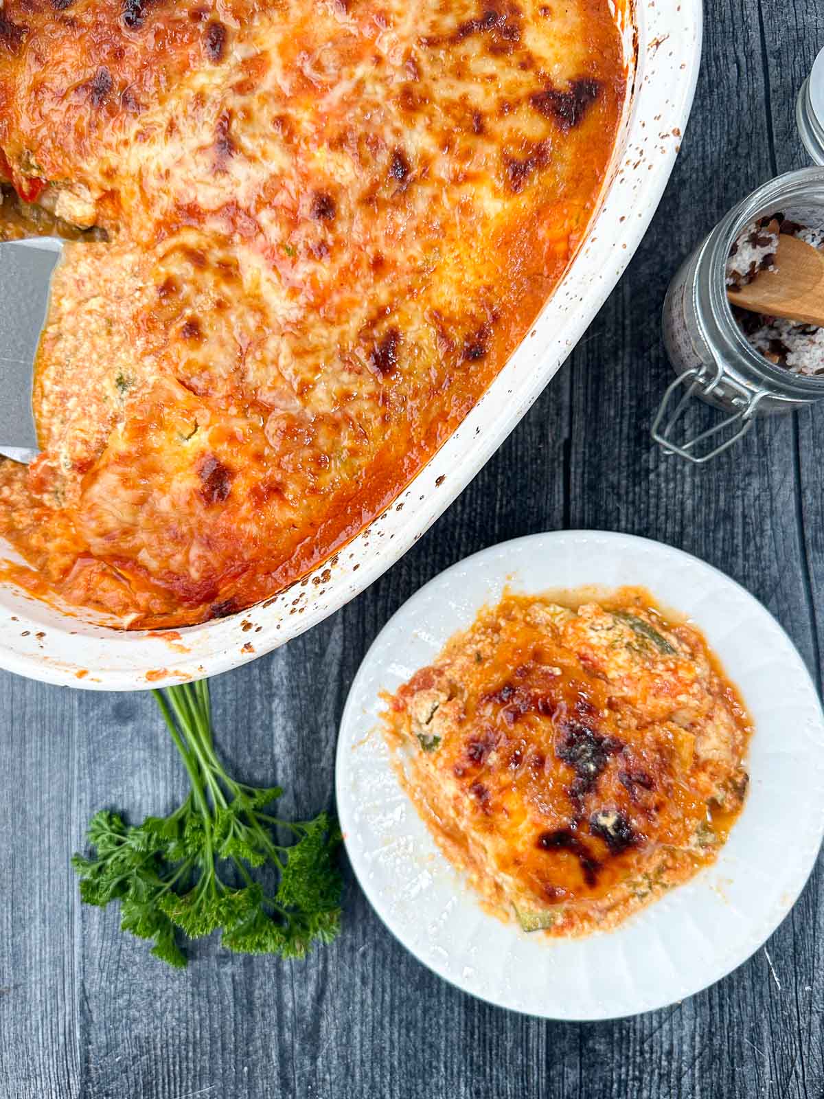 aerial view of pan and dish with veggie lasagna and fresh parsley