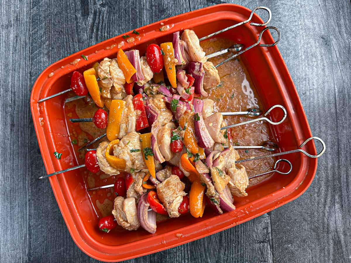 Marinating container with the chicken and veggie kebabs.