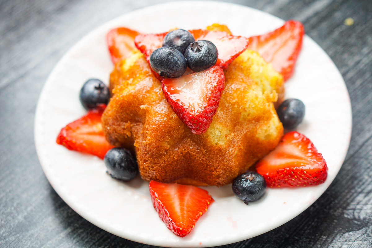 closeup of a white plate with min keto lemon pound cake with macerated berries
