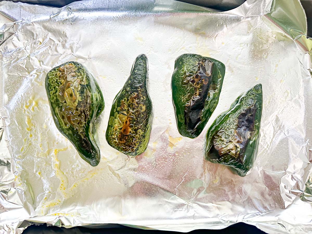 cookie sheet with aluminum foil and blistered grilled poblano peppers