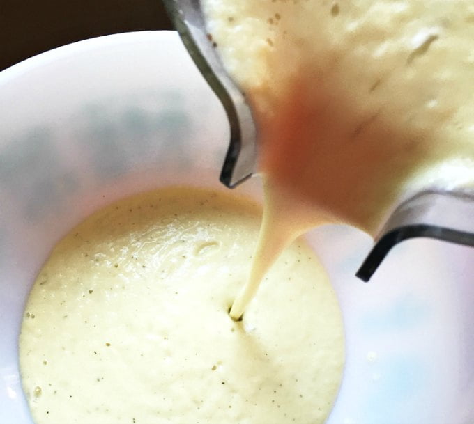 low carb cauliflower cream mixture being poured from blender pitcher into a bowl