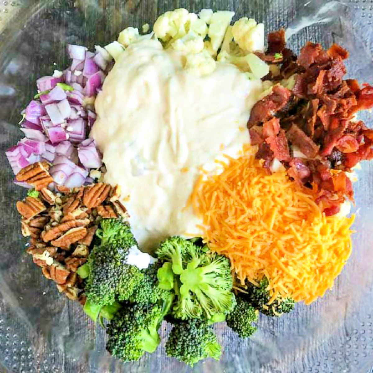 ingredients for the salad - pecan, bacon, keto dressing, cauliflower, broccoli, cheddar, red onions