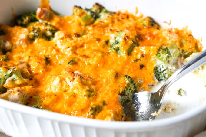 white baking dish with broccoli chicken casserole and a spoon