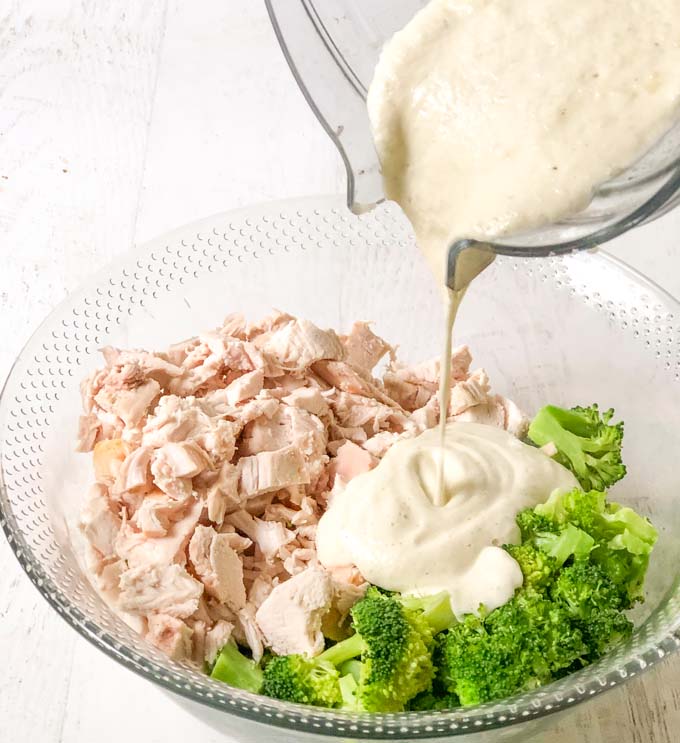 bowl of diced chicken and broccoli with cauliflower cream pouring on it
