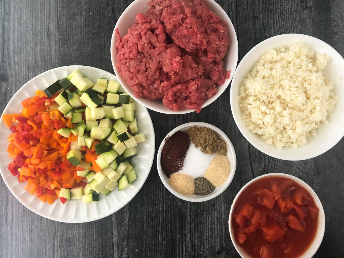 recipe ingredients - chopped veggies, spices, ground beef, tomatoes and cauliflower rice