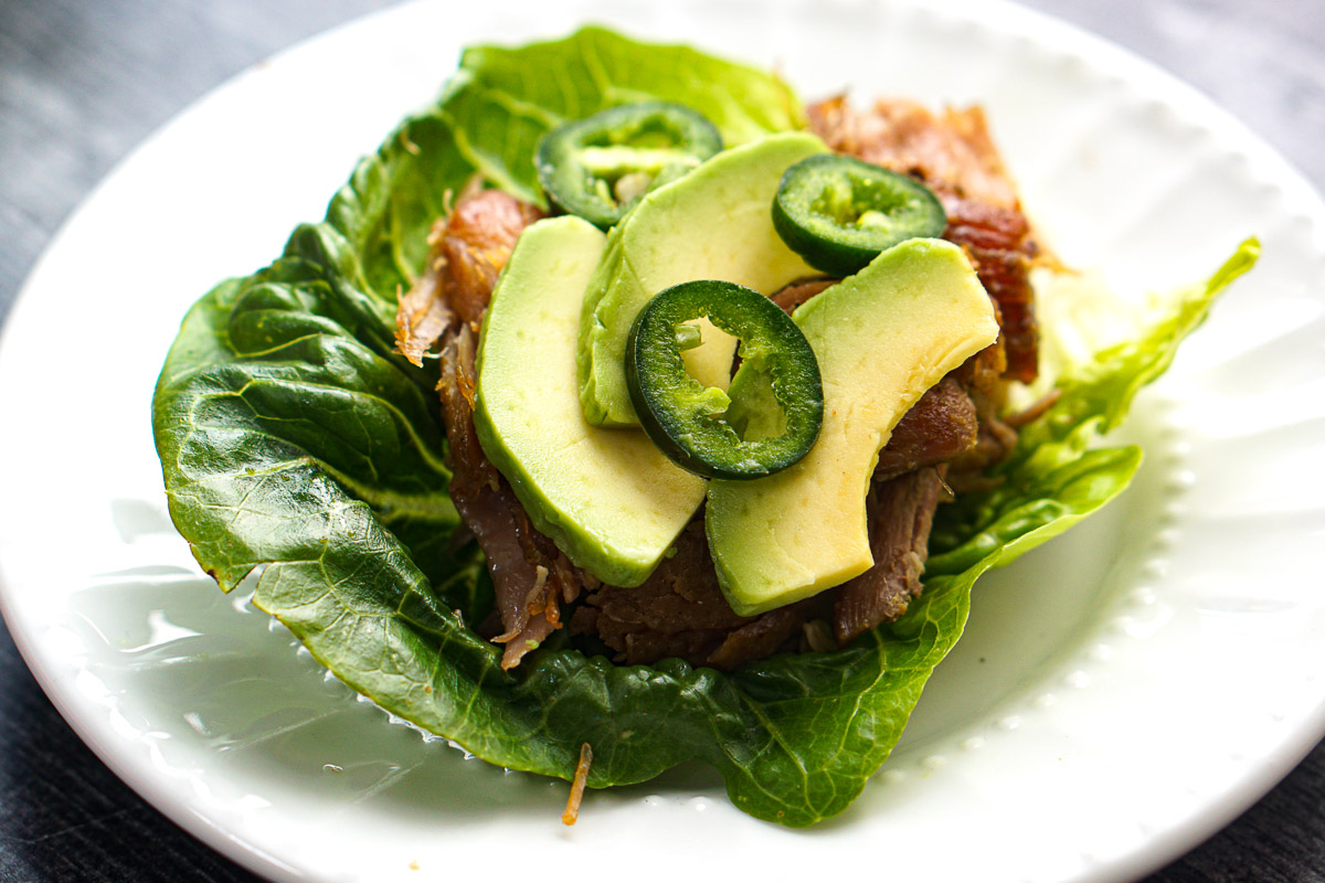 Closeup of a white plate with carnitas lettuce wrap. 