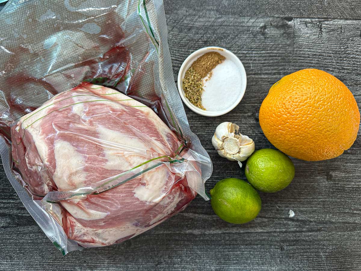Recipe ingredients - pork shoulder, spices, oranges, limes and garlic.
