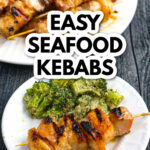 White plate with a seafood kebab and a serving of pesto broccoli and the platter in the background and text.