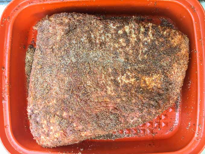 rubbed raw brisket in marinating container