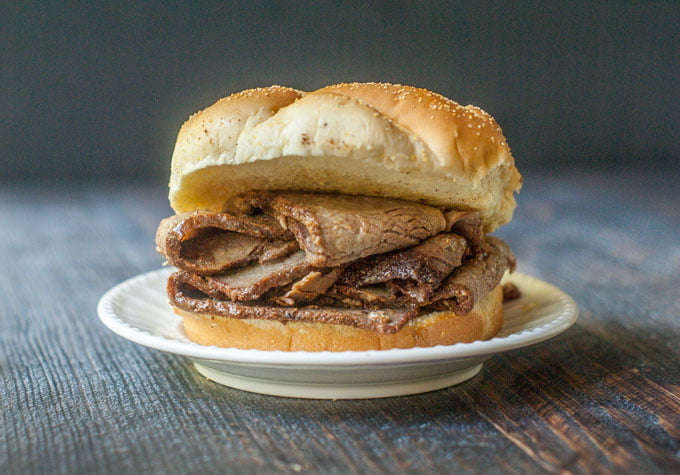 smoked barbecue brisket on a sandwich bun on white plate