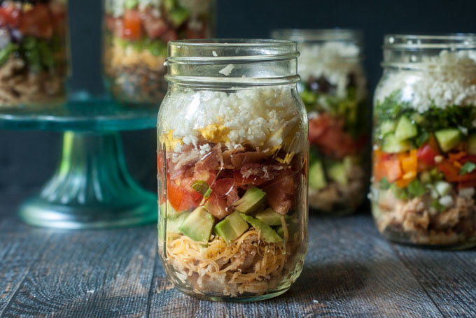 Chicken Cobb salad in a jar with other jars in the background