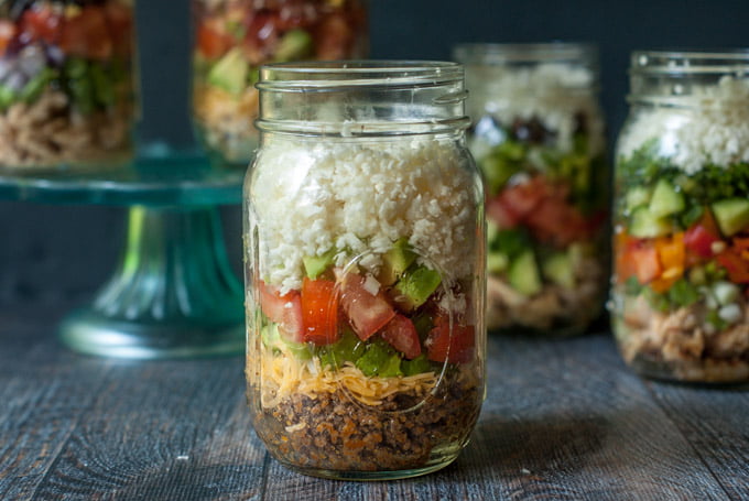 Mexican taco salad in a jar with other jars in the background