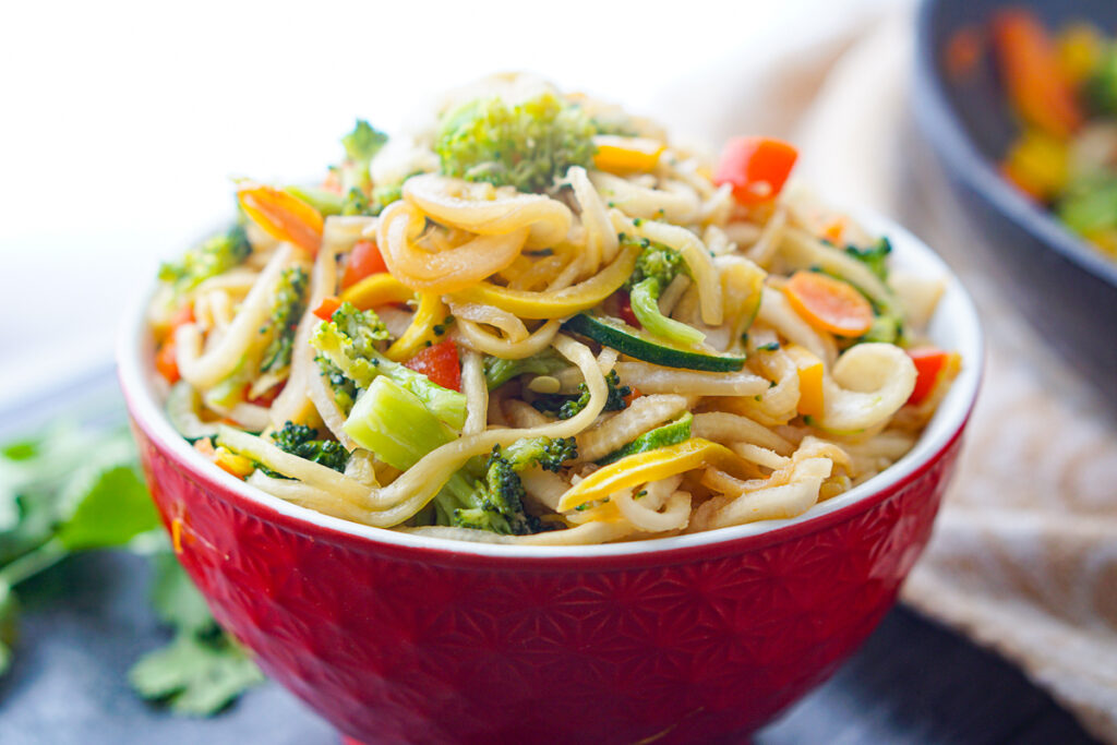 red bowl with finished veggie noodles with stir fried veggies