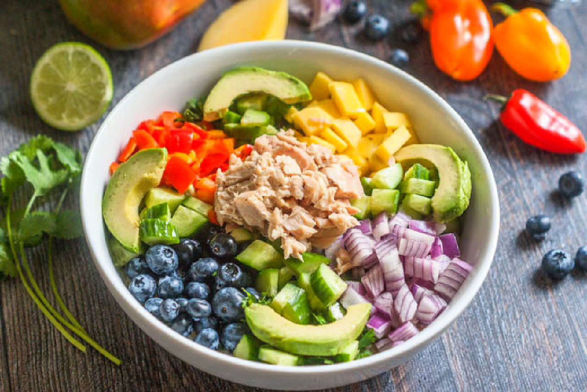 White bowl with tuna and fruit and cauliflower rice as the base instead of lettuce.