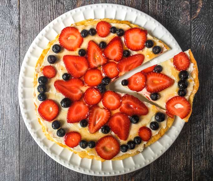 fathead fruit pizza on white plate with a slice cut