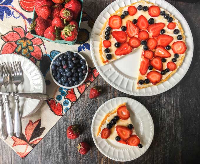 aerial view of fathead fruit pizza with strawberries and blueberries on white plates 