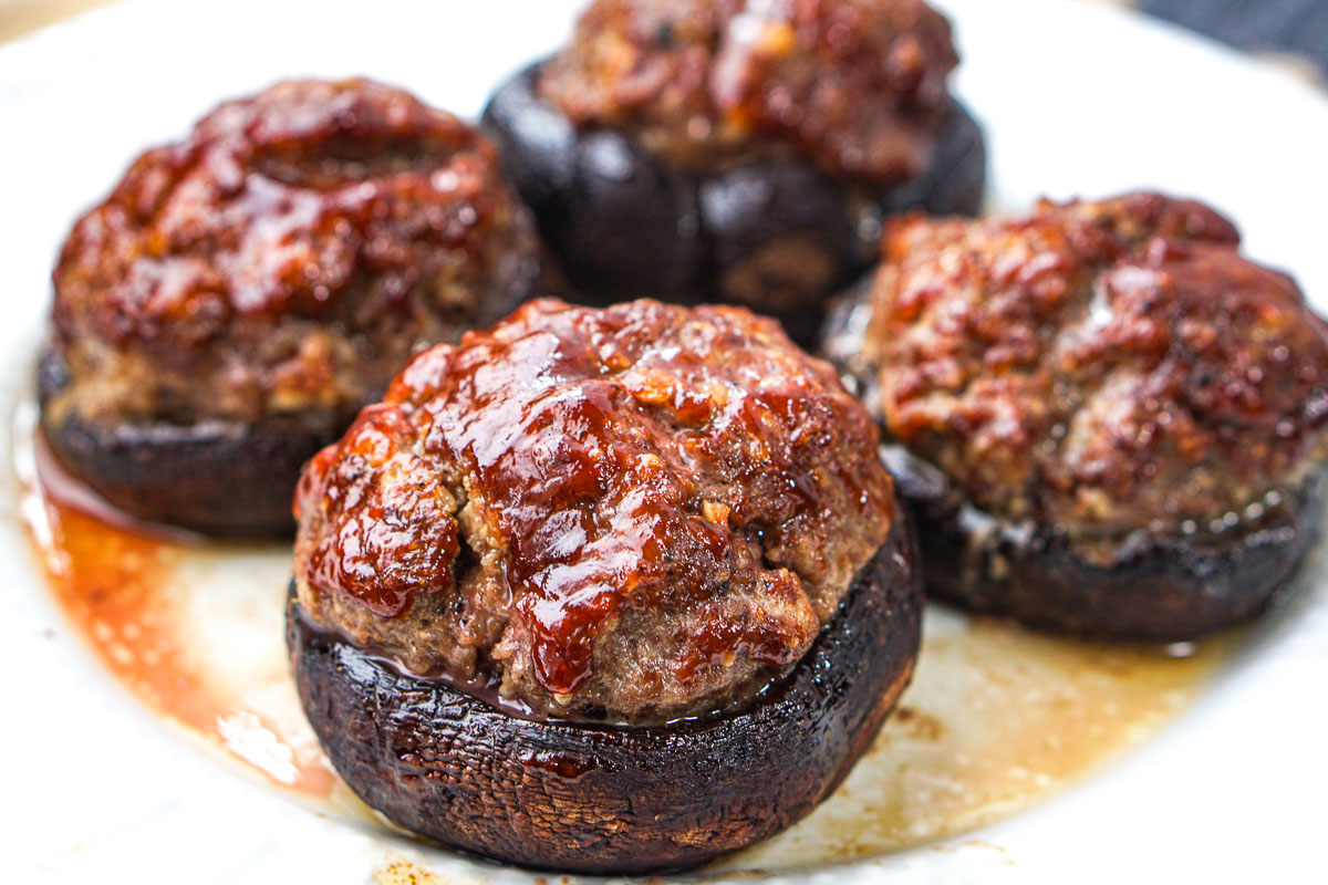 closeup of 4 mushroom caps stuffed with keto meatloaf