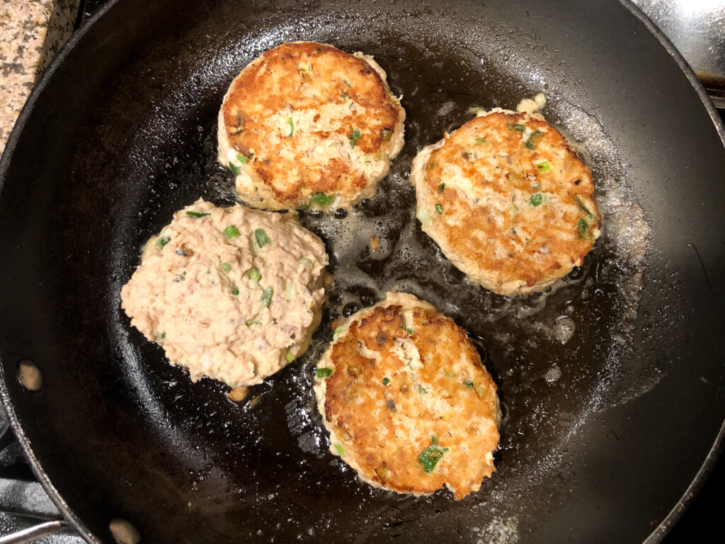 pan with 4 salmon patties frying