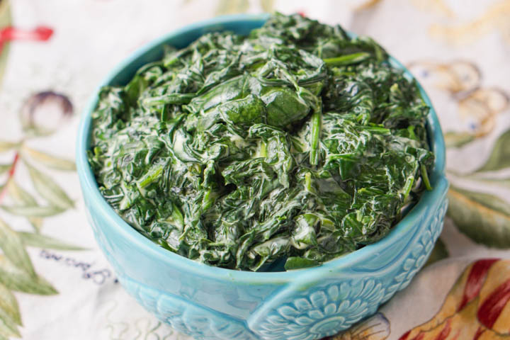 blue bowl filled with creamed spinach made in a slow cooker with 3 ingredients 