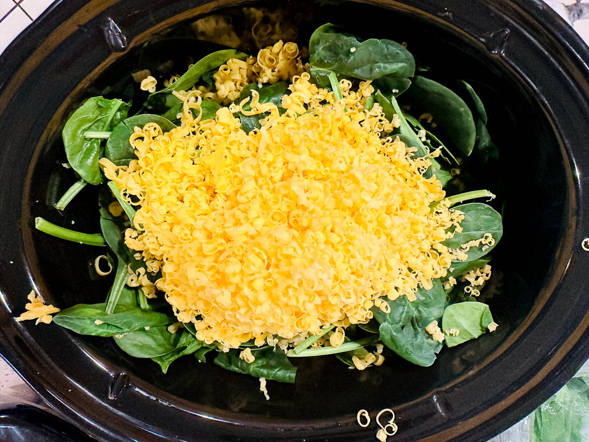 black crock with raw spinach and shredded cheese