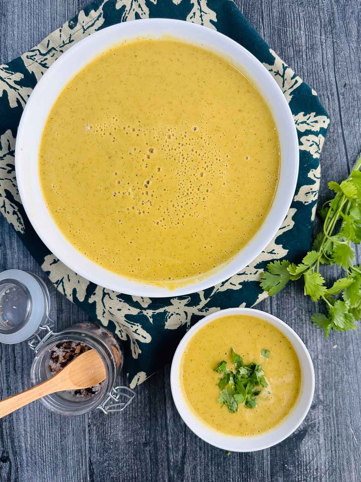 Aerial view of two white bowls with Thai curry creamy zucchini soup.
