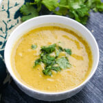 White bowl with keto creamy zucchini soup with Thai curry flavor.