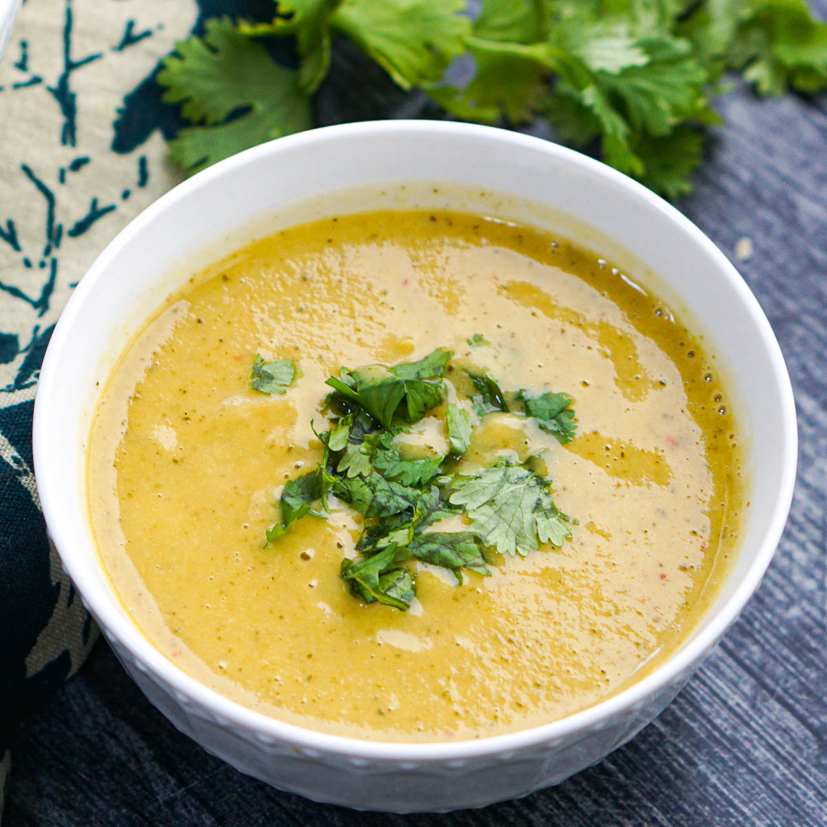 White bowl with keto creamy zucchini soup with Thai curry flavor.