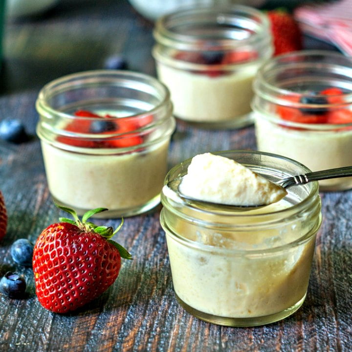 glass jar with keto vanilla mousse with a spoon full on top and a strawberry