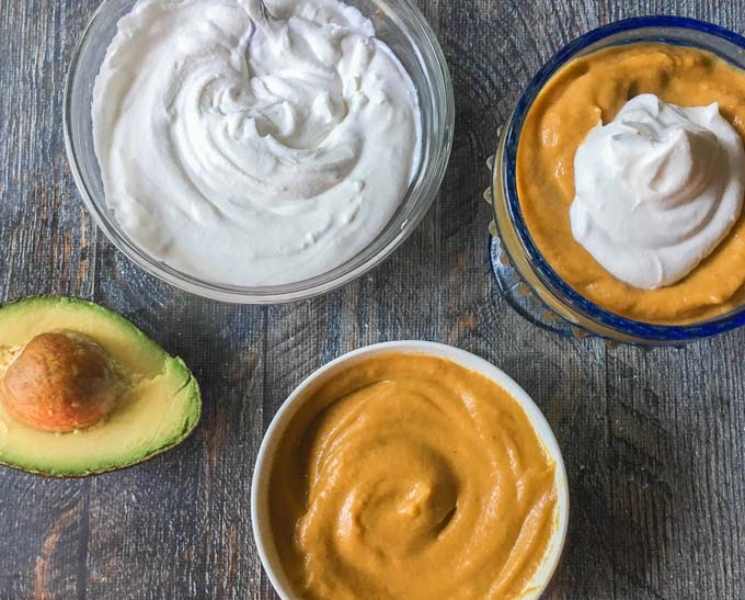 dishes of healthy pumpkin pie pudding, an avocado half and bowl of coconut whipped cream