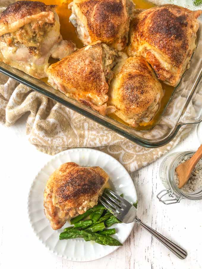 low carb stuffed chicken thigh on white plate  and in baking dish with asparagus