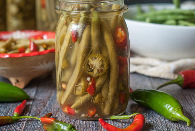 glass jar with pickled green beans, with jalapenos and  serene peppers slices