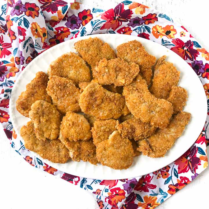 white platter with low carb breaded pork tenderloin cutlets on floral cloth