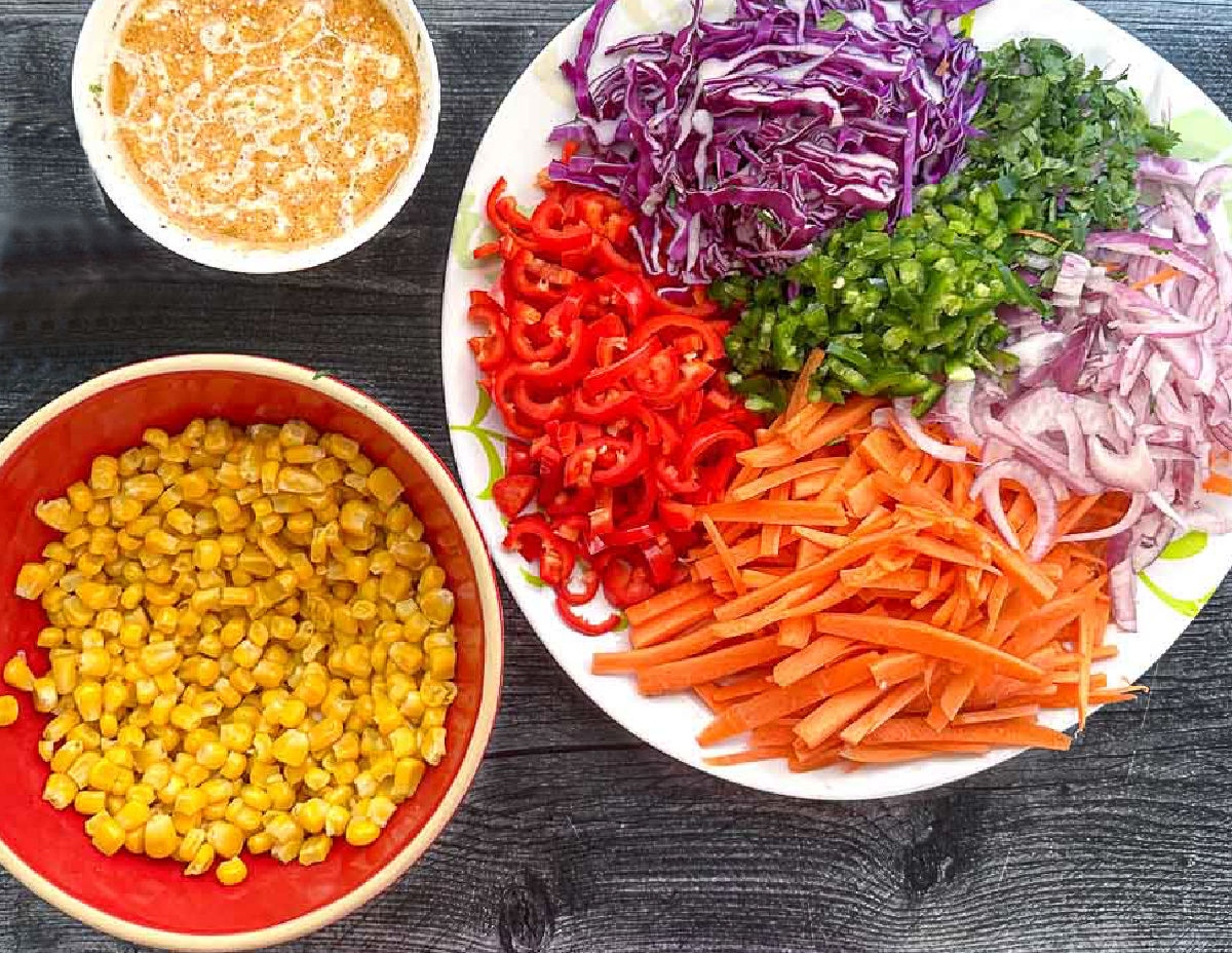 recipe ingredients - bowl of Mexican dressing, red bowl with corn and plate with chopped vegetables