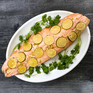 White platter with margarita salmon and parsley sprigs.