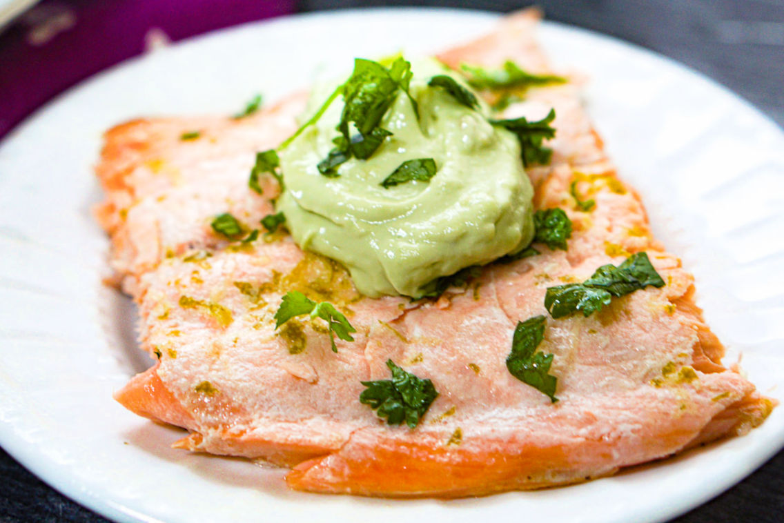 Closeup of a serving of the fish with avocado dip on top.