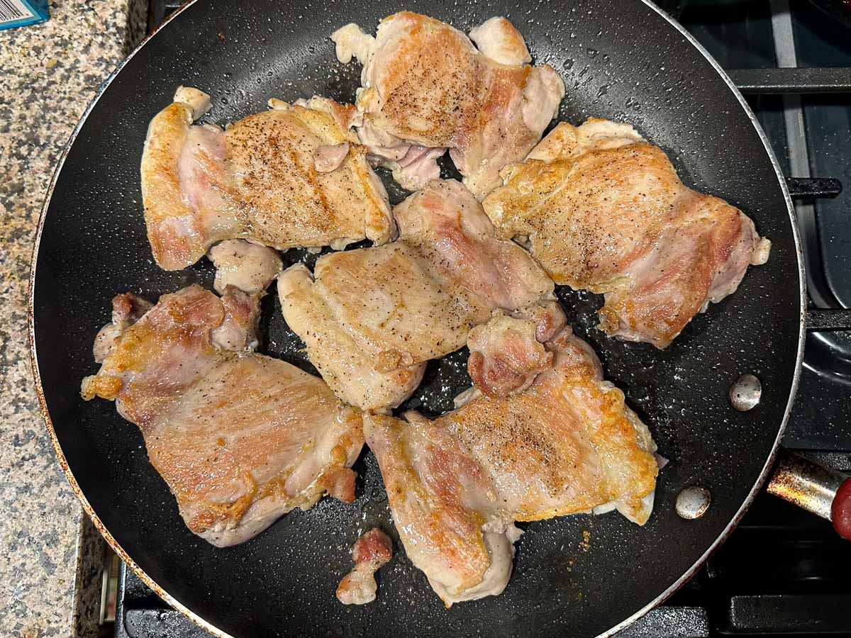 skillet with chicken thighs browning