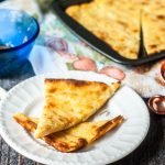 white plate with garlic flatbread and cookie sheet in background