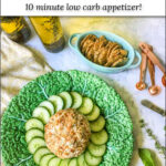 green plate with keto goat cheese ball with cucumbers and crackers and text