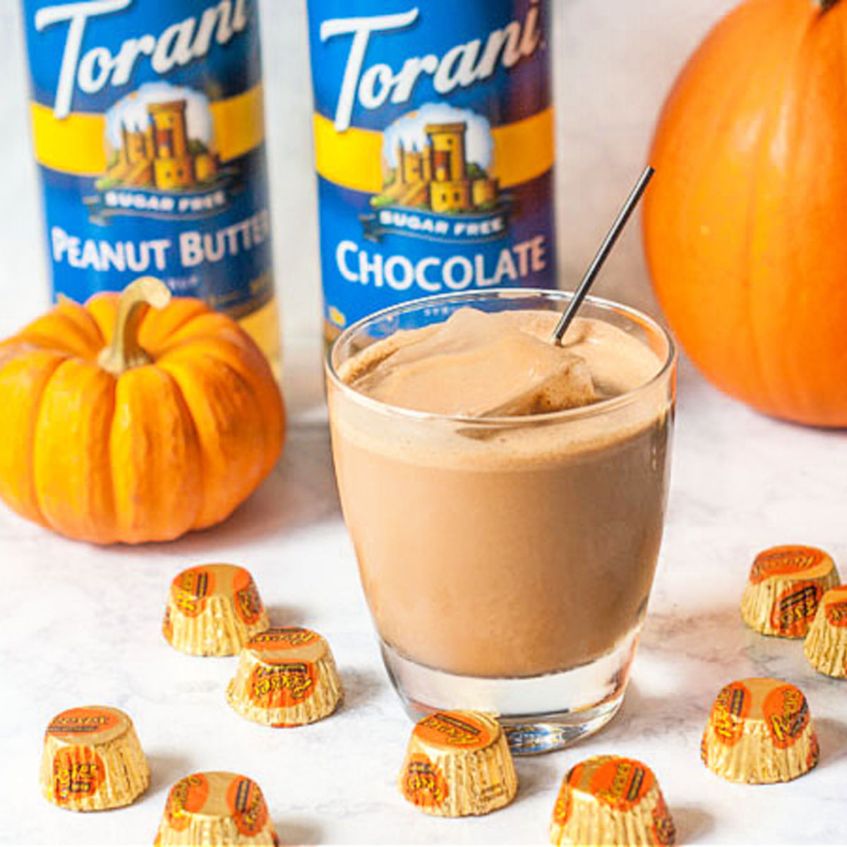 Reeses cup flavored keto Halloween candy drinks with mini Reeseand pumpkins in the background