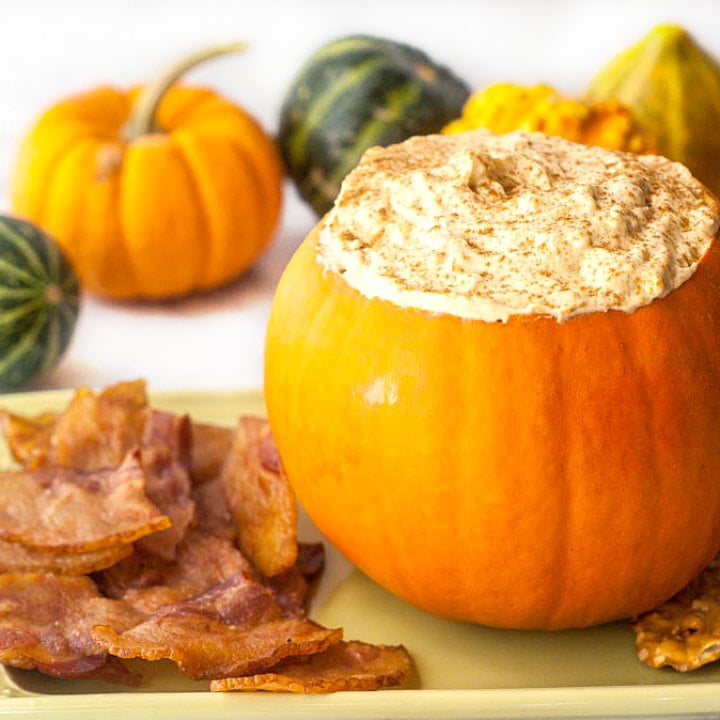 pumpkin filled with keto pumpkin cheesecake dip with bacon chips and gourds in the background