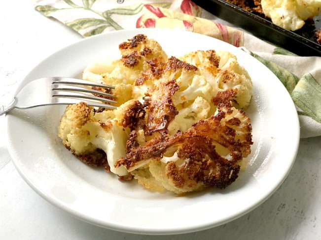 white plate with roasted rosemary parmesan cauliflower bites with a fork