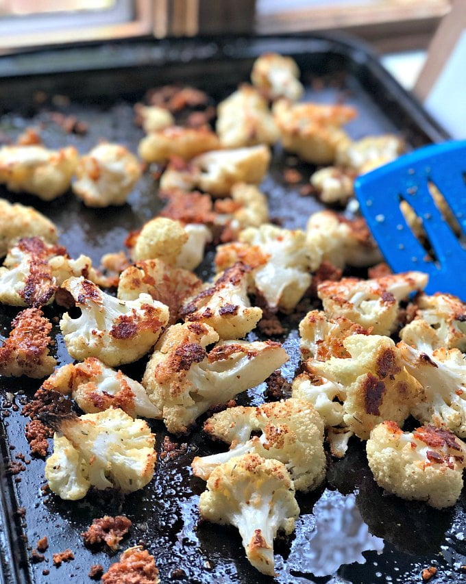 baking sheet with baked parmesan cauliflower and blue spatula