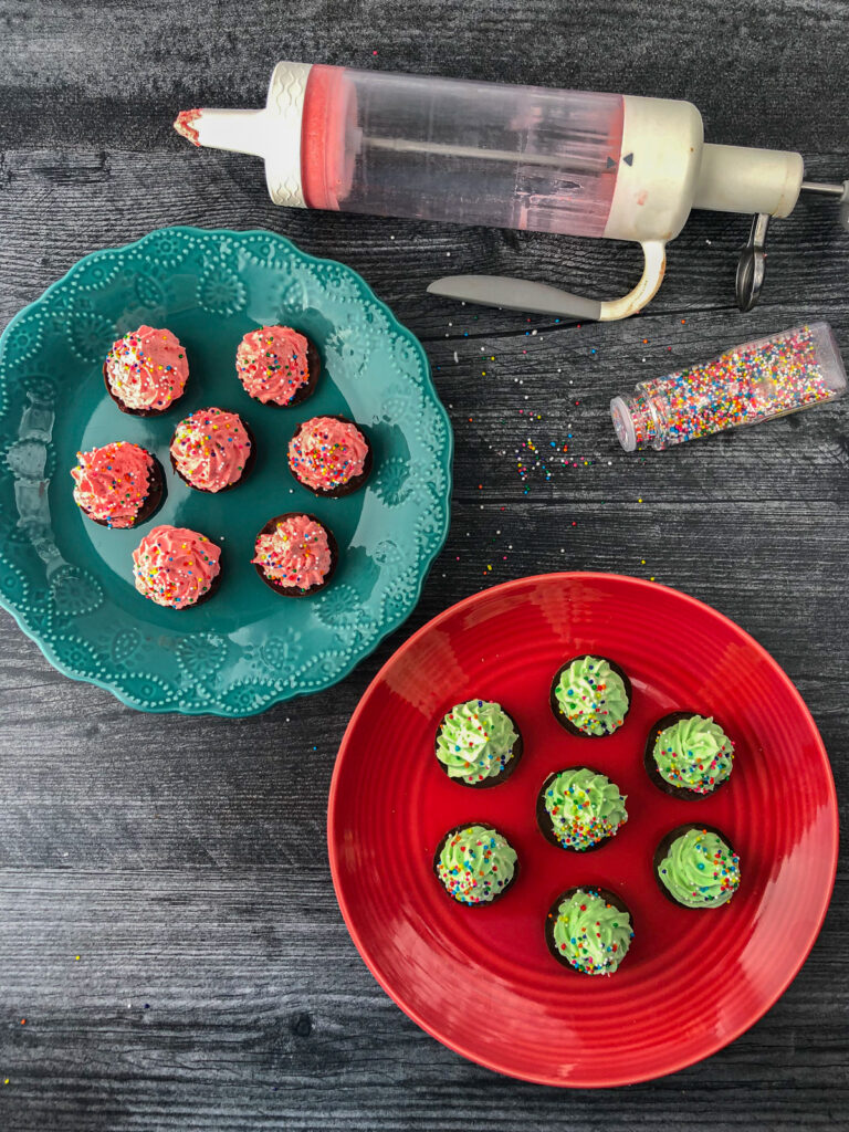 green and red plates with sugar free Christmas trees made from keto mousse recipe and a bottle of sprinkle and icing gadget